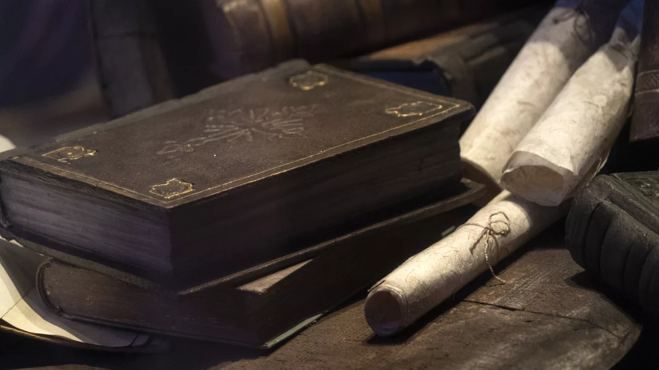 Antique leather books beside rolled parchment in warm, low light